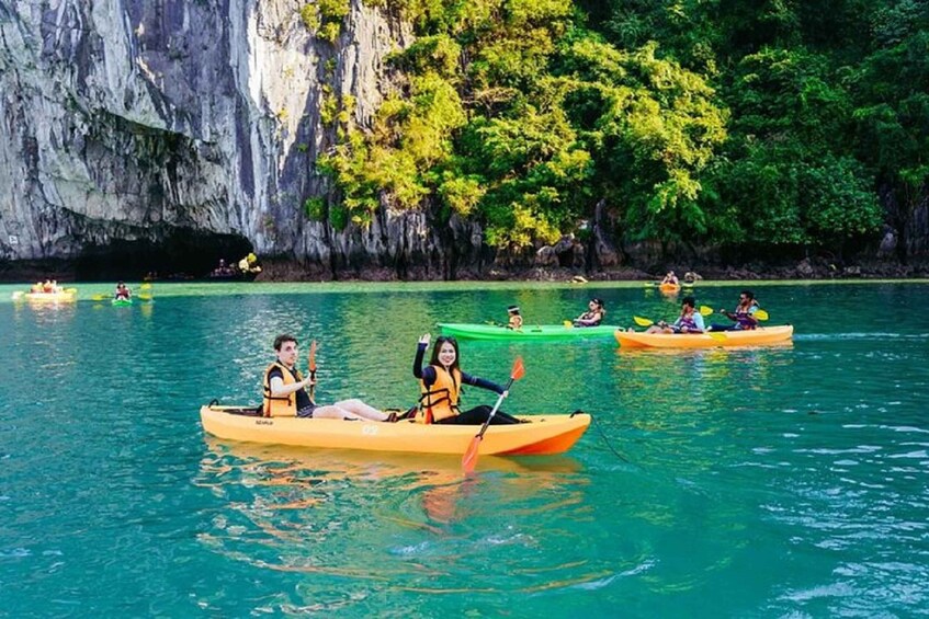 People kayaking on a calm sea with cliffs in the background. 1