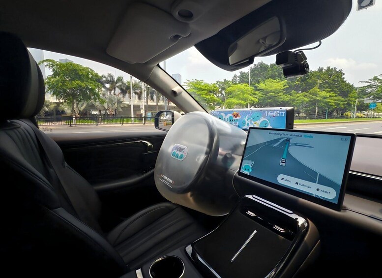 A car's interior with a digital navigation screen displaying a route and a sticker on the steering wheel. 1