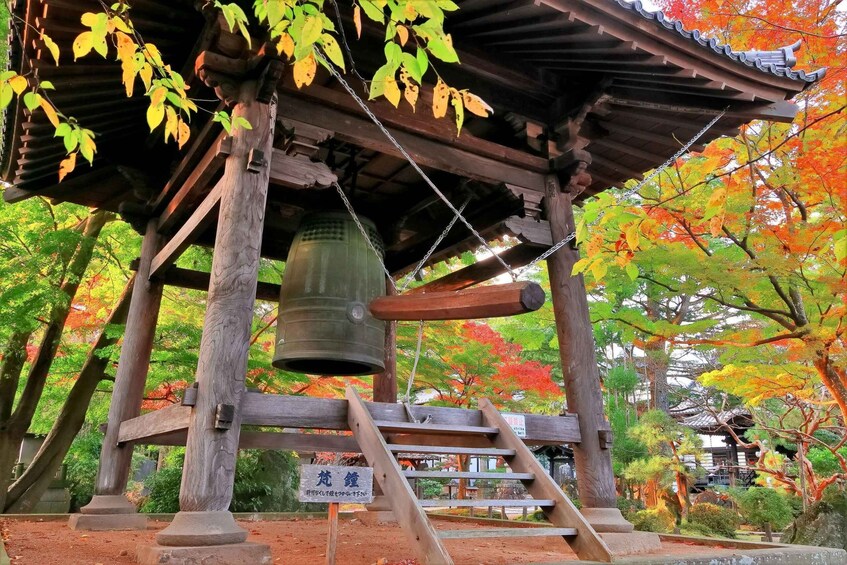 A traditional Japanese structure with a bell, surrounded by autumn foliage. 2
