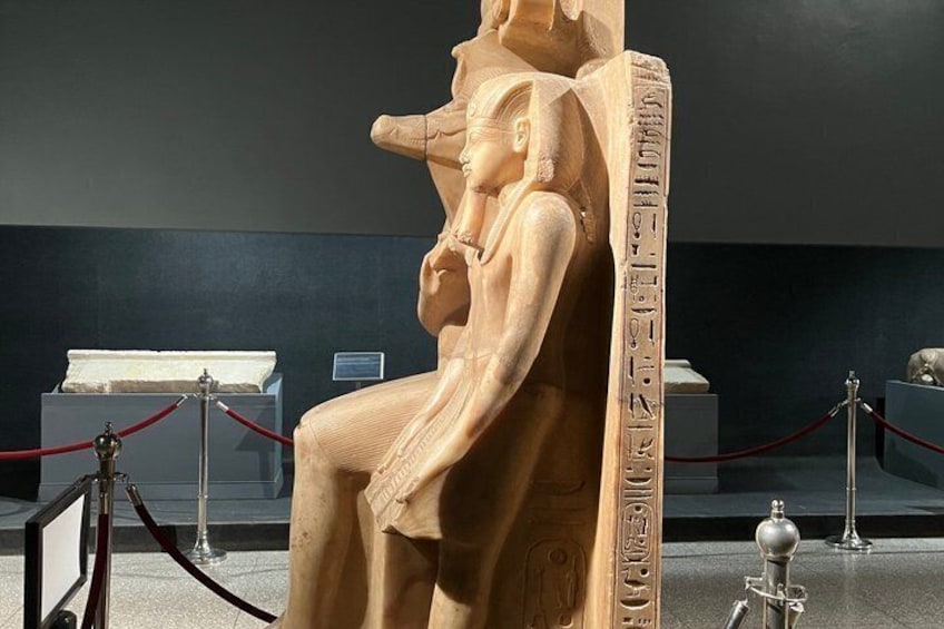 En stor, detaljerad, forntida egyptisk sarkofag med hieroglyfer, utställd i ett museum och omgiven av skyddsbarriärer. 1