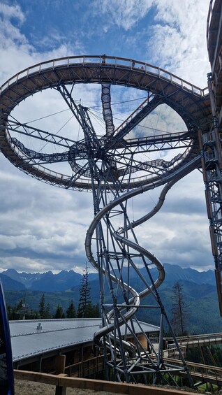 A large, intricate radio telescope structure with a circular dish, set against a backdrop of mountains and a cloudy sky. 4