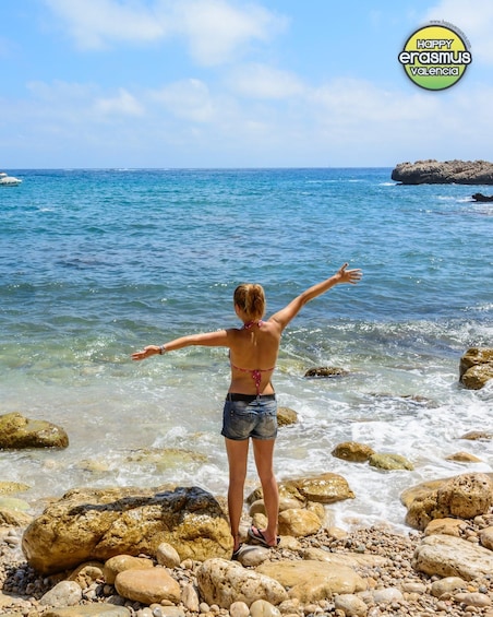 A person standing on rocks by the sea, facing the water. 3