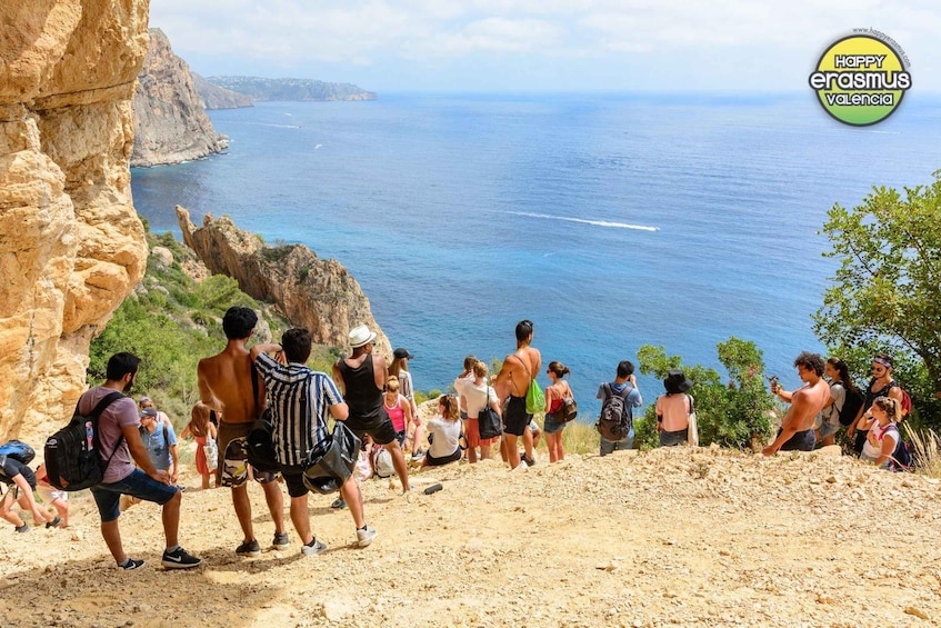 A group of people hiking on a rocky path with a view of the sea and cliffs. 5