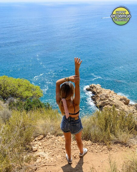 A person standing on a rocky outcrop overlooking a coastal sea. 2