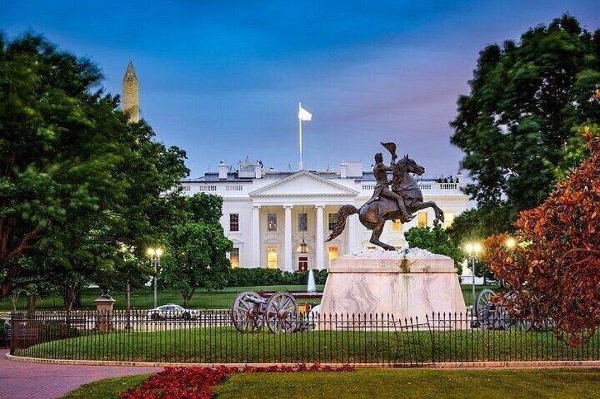 A statue of a man on horseback in front of the White House, with a fence and trees around. 3