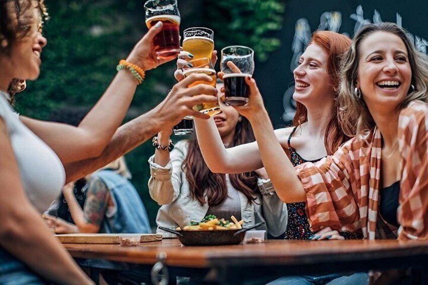 A group of people toasting with drinks at a table outdoors. 2