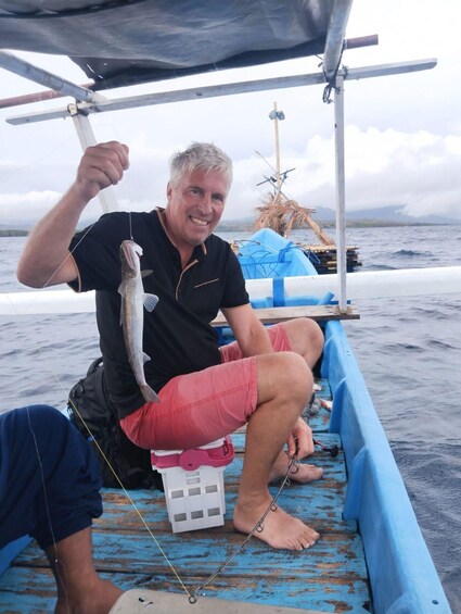 A person holding a fish on a boat. 5