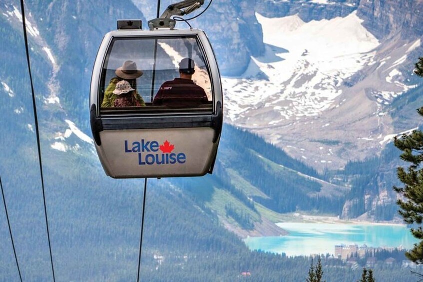 A cable car with 'Lake Louise' written on it, passengers, and a mountainous landscape with a lake. 1