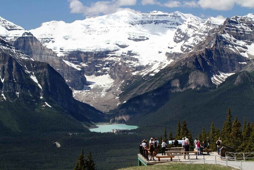 A mountainous landscape with a lake and a group of people at a viewpoint. 2