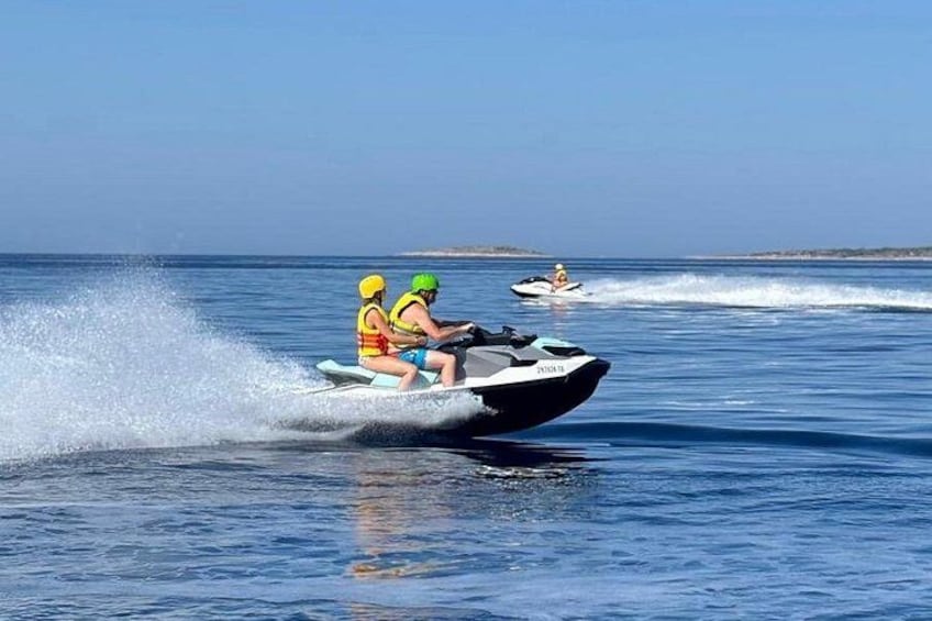 Dos personas practican esquí acuático sobre el agua, con otra moto acuática al fondo. 1