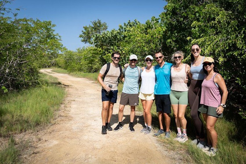Un grupo de personas de pie en un sendero de tierra rodeado de vegetación. 2
