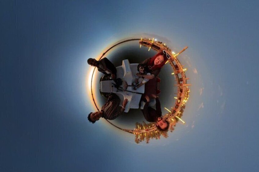 A group of people seated around a table with a circular light decoration. 1