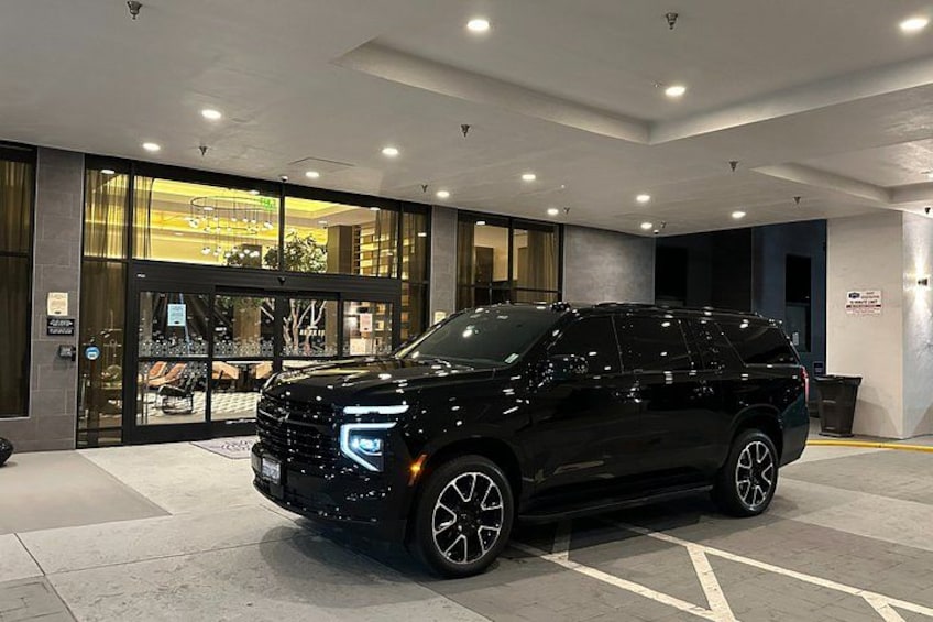 Un VUS noir était garé dans un parking intérieur bien éclairé, dont l’entrée en verre menait à un bâtiment. 2
