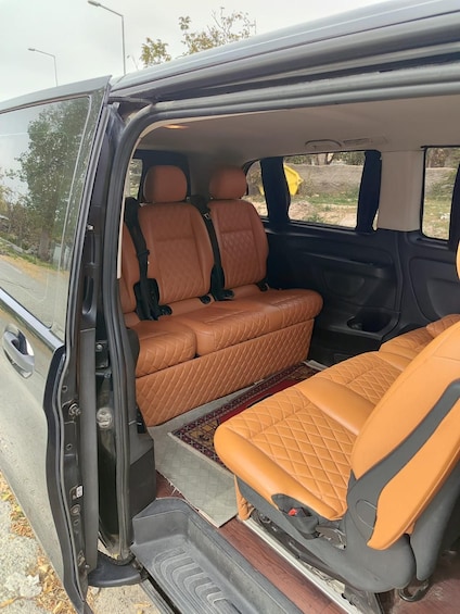 A vehicle interior with orange quilted seats and a patterned floor mat. 1