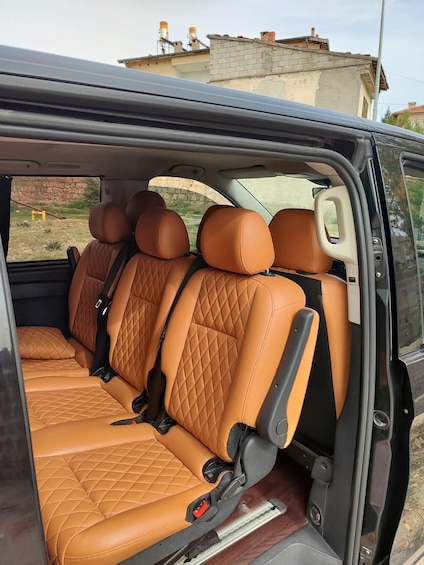 A vehicle interior with tan leather seats and a visible seatbelt. 5