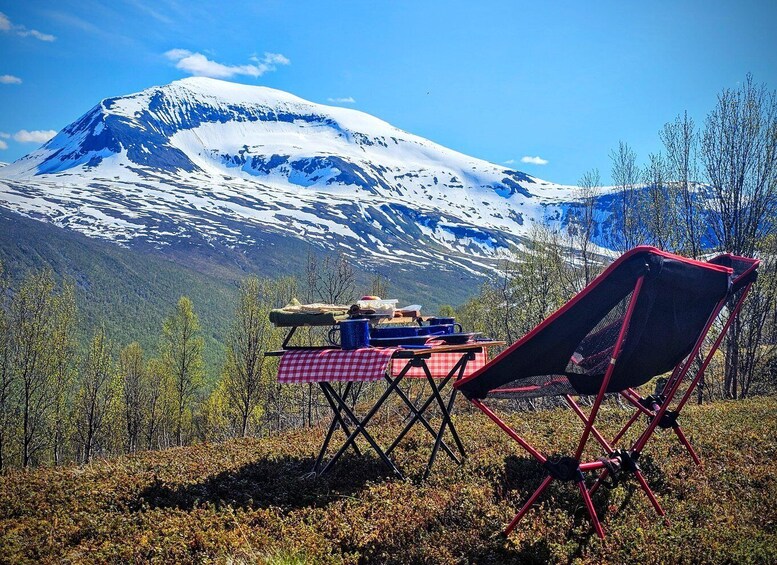 A snow-capped mountain, a red folding chair, and a picnic setup with a checkered tablecloth. 3