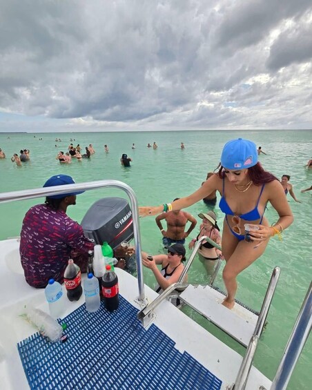 A boat with people on the deck and others swimming in the water. 2