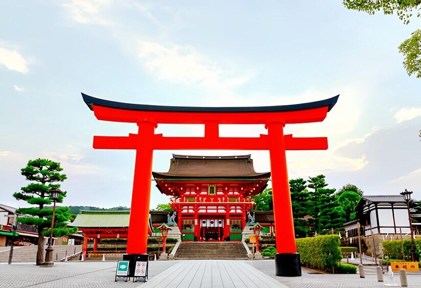 A traditional Japanese torii gate with a red frame and a green roof, leading to a building with a tiled roof. 5
