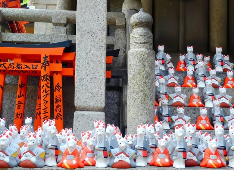 A shrine with orange torii gates and numerous cat statues in traditional attire. 3
