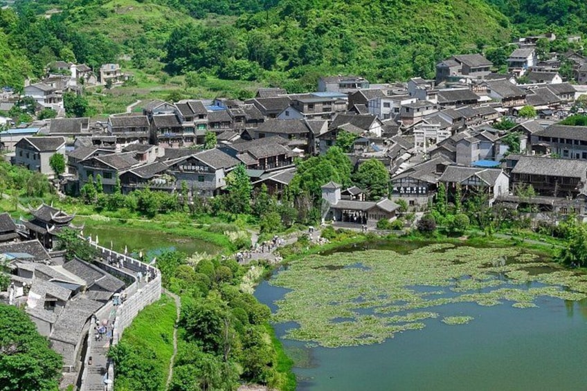 A traditional village with terraced houses, a river, and a stone bridge. 2