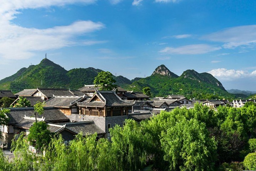 A traditional village with wooden houses, lush greenery, and mountains in the background. 3