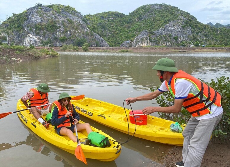 Two people in yellow kayaks on a calm river with a mountainous backdrop. 1