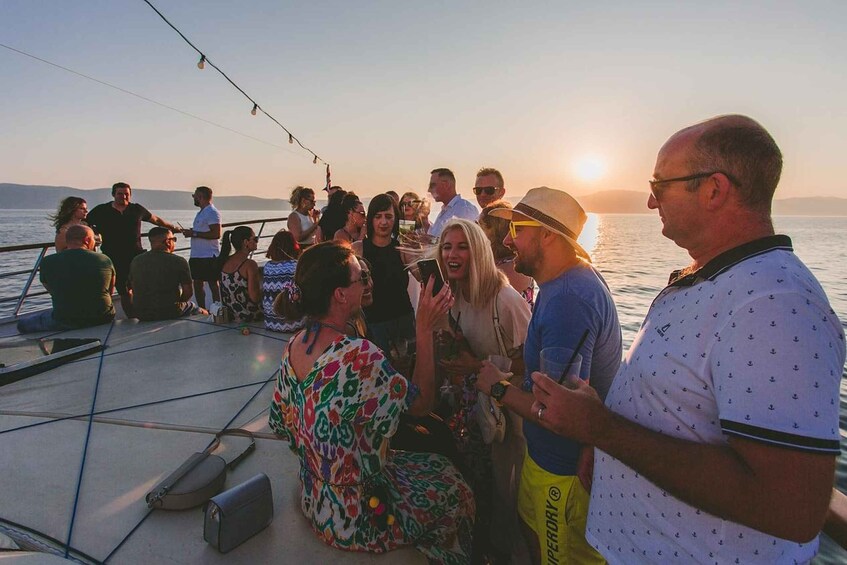 A group of people on a boat with the sun setting in the background. 5