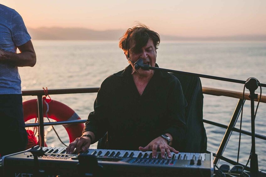 A person playing a keyboard on a boat with a lifebuoy visible in the background. 2
