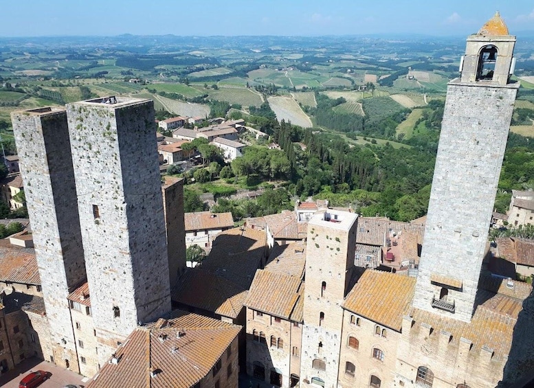 A historic town with prominent stone towers and terraced vineyards in the background. 1