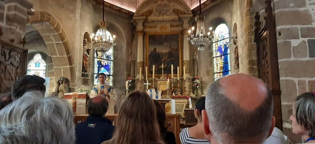 A church interior with a congregation, altar, stained glass windows, and statues. 5