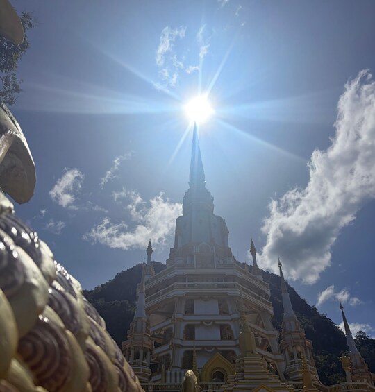 A temple with a tall spire and golden decorations, surrounded by mountains and a clear sky. 5