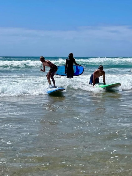 Three surfers on the beach with their surfboards. 4