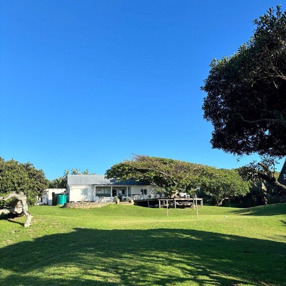 A house with a white exterior and a grey roof, surrounded by a well-maintained lawn and trees. 2