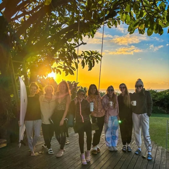 A group of people on a wooden deck with a sunset in the background. 5
