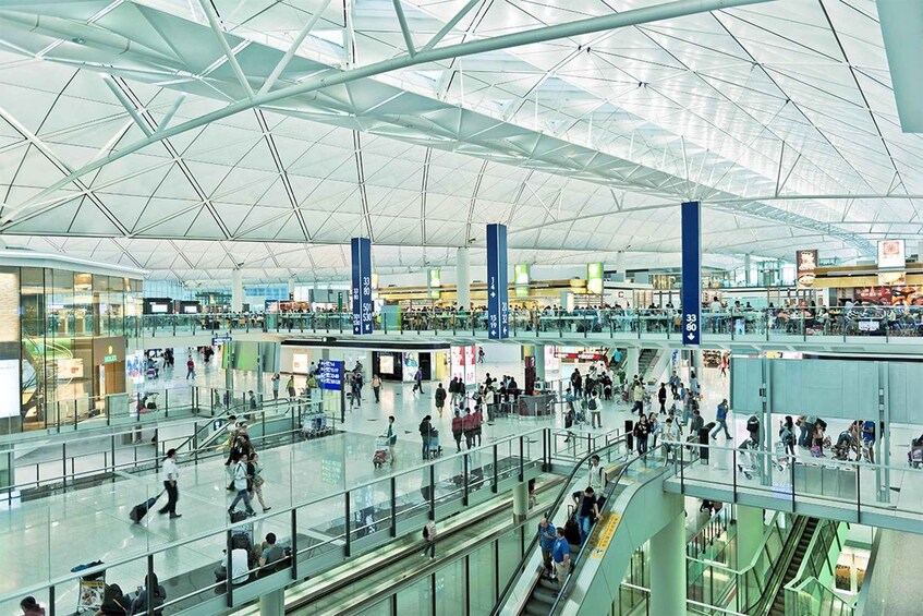 A spacious airport terminal with multiple levels, glass railings, and a high ceiling with a geometric pattern. 1