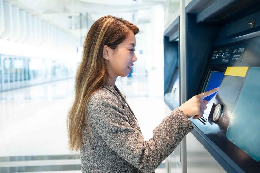 A person using a self-service kiosk in a modern indoor setting. 2