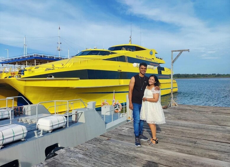A couple standing on a wooden dock with a yellow boat in the background. 3