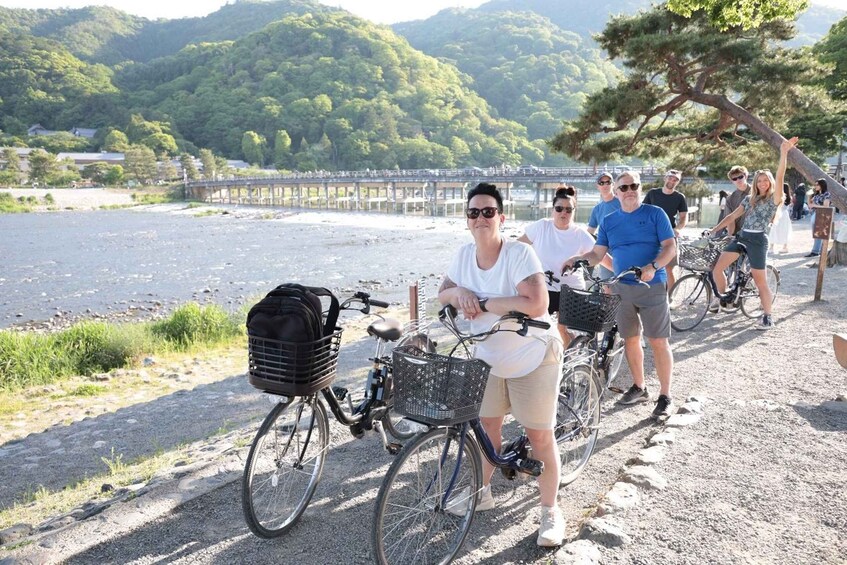 A group of people on bicycles near a lake with a bridge in the background. 4