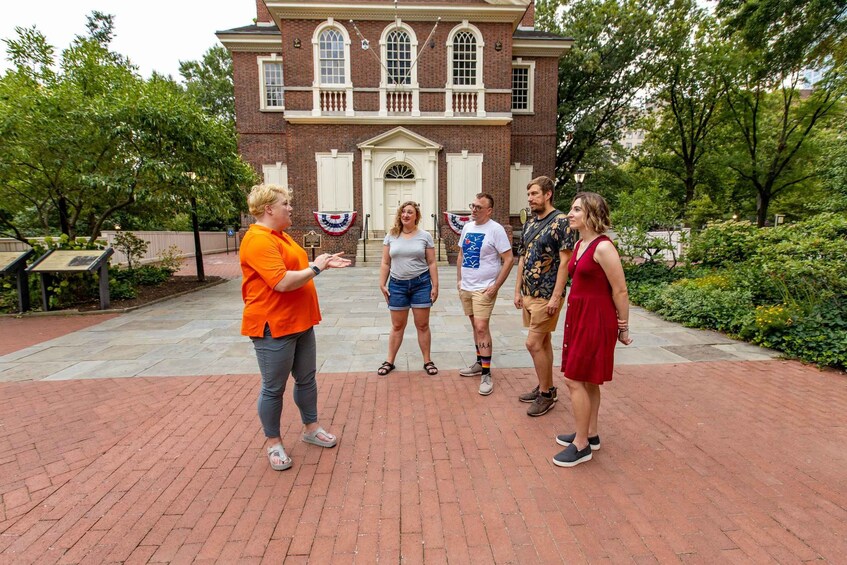 A group of people standing in front of a historic building with a brick facade and arched windows. 3