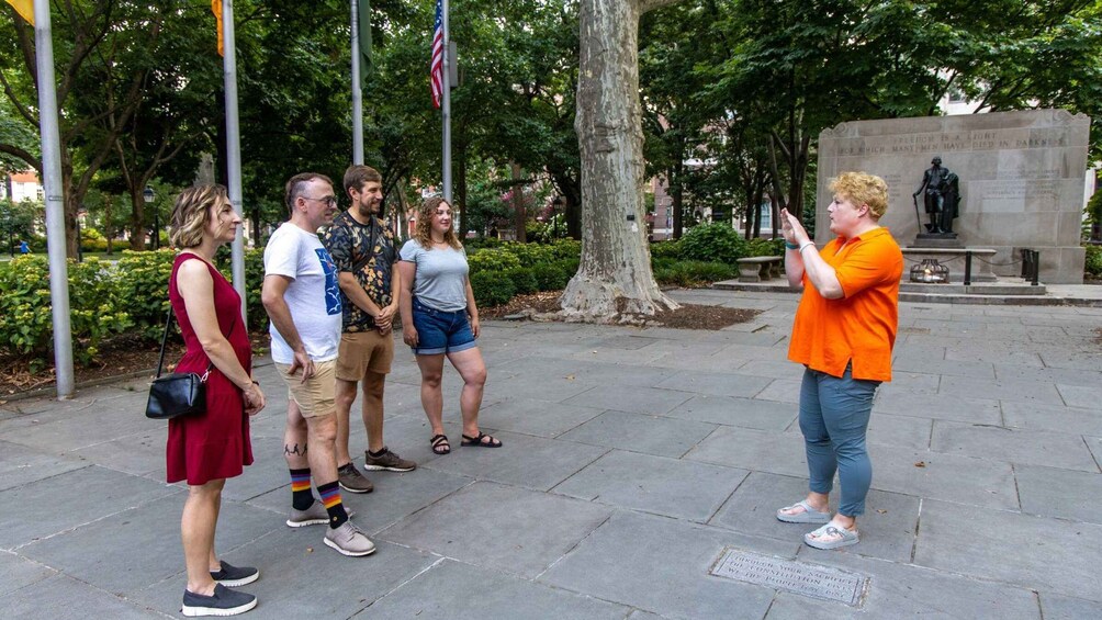 A group of people standing in a park with a statue and a flagpole in the background. 5