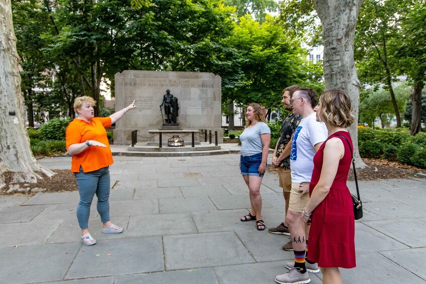 A group of people standing in a park with a statue and a monument in the background. 4