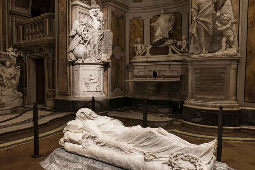 A marble sarcophagus with a reclining figure, surrounded by classical sculptures and architectural details. 1