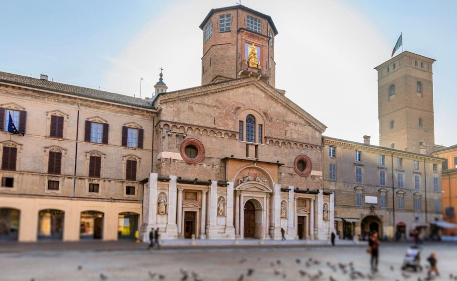 A historic building with a bell tower, arched windows, and statues. 3