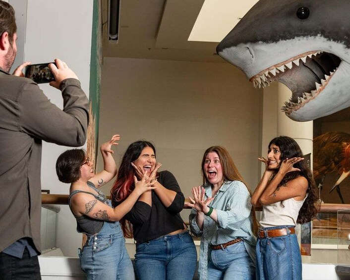A group of people in a room with a large shark model. 1