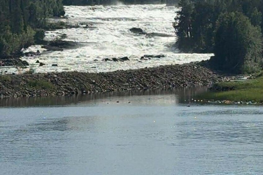 A river with a rocky shoreline and a forested hill in the background. 4