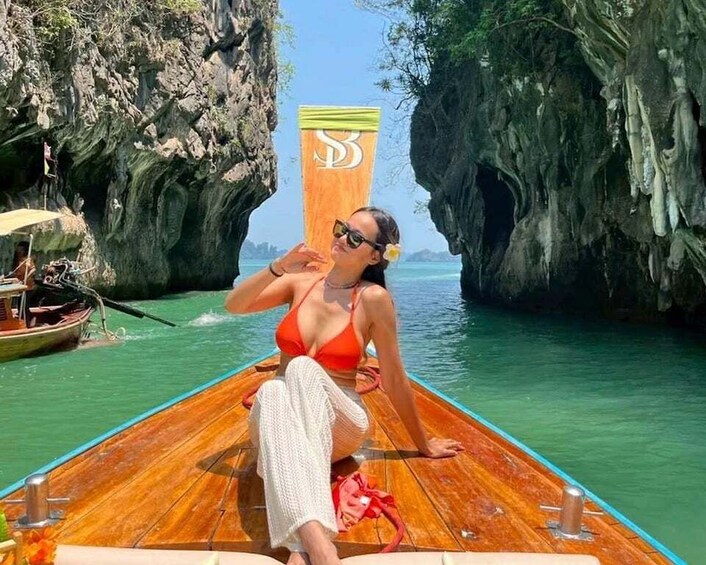 A person on a wooden boat in a narrow waterway flanked by rocky cliffs. 1