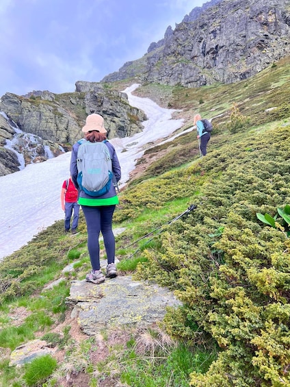 Hikers on a rocky mountain trail with a glacier in the background. 3