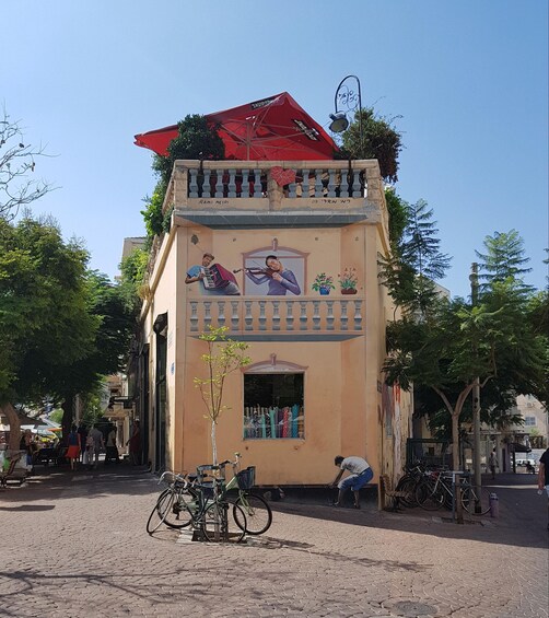 A building with a mural of two musicians, a red awning, and bicycles parked in front. 1