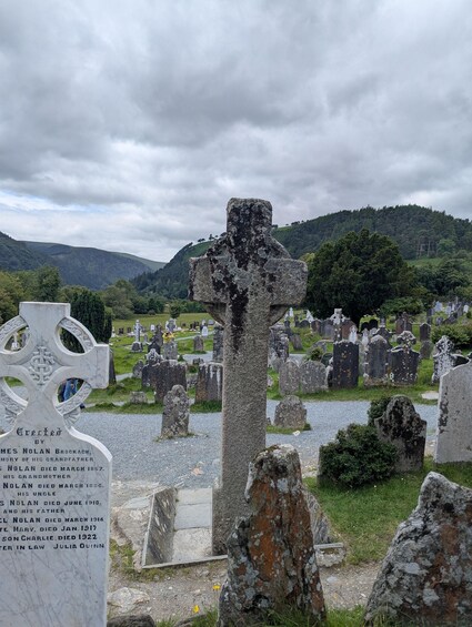 A cemetery with gravestones, a large cross, and a memorial plaque. 4