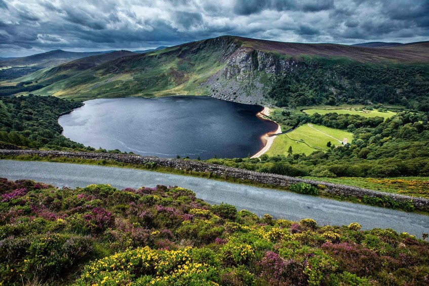 A lake surrounded by hills, a road, and a stone wall. 1